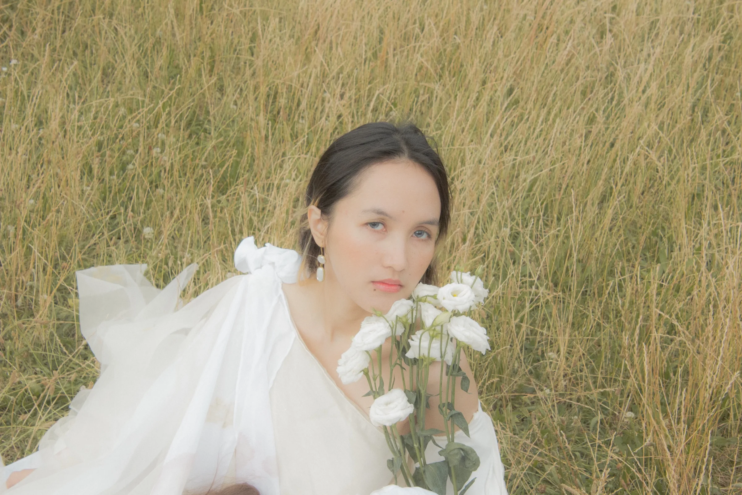 Portrait of a model holding white lisianthus, looking to camera