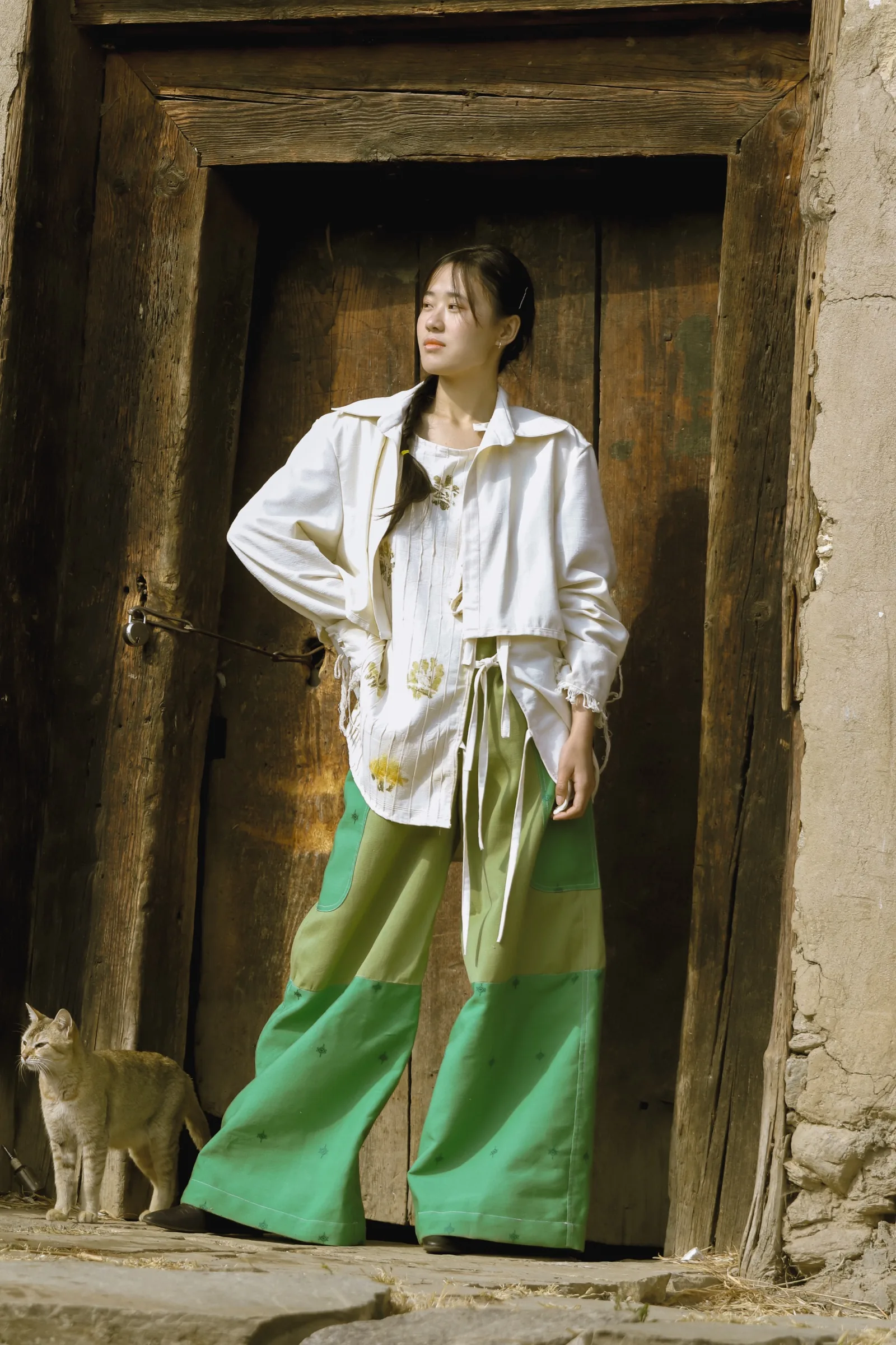 In a doorway with a village cat, eco-printed jacket and green trousers