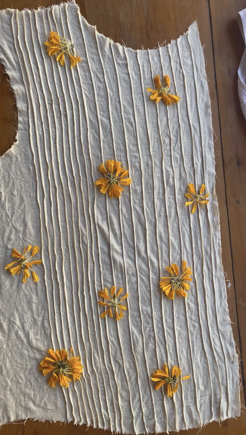 Marigold flowers pinned across the pleated dress front before steaming